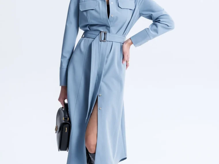 Woman in a blue belted dress and glasses in a studio