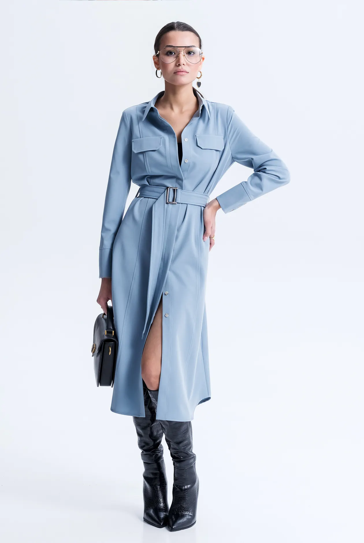 Woman in a blue belted dress and glasses in a studio