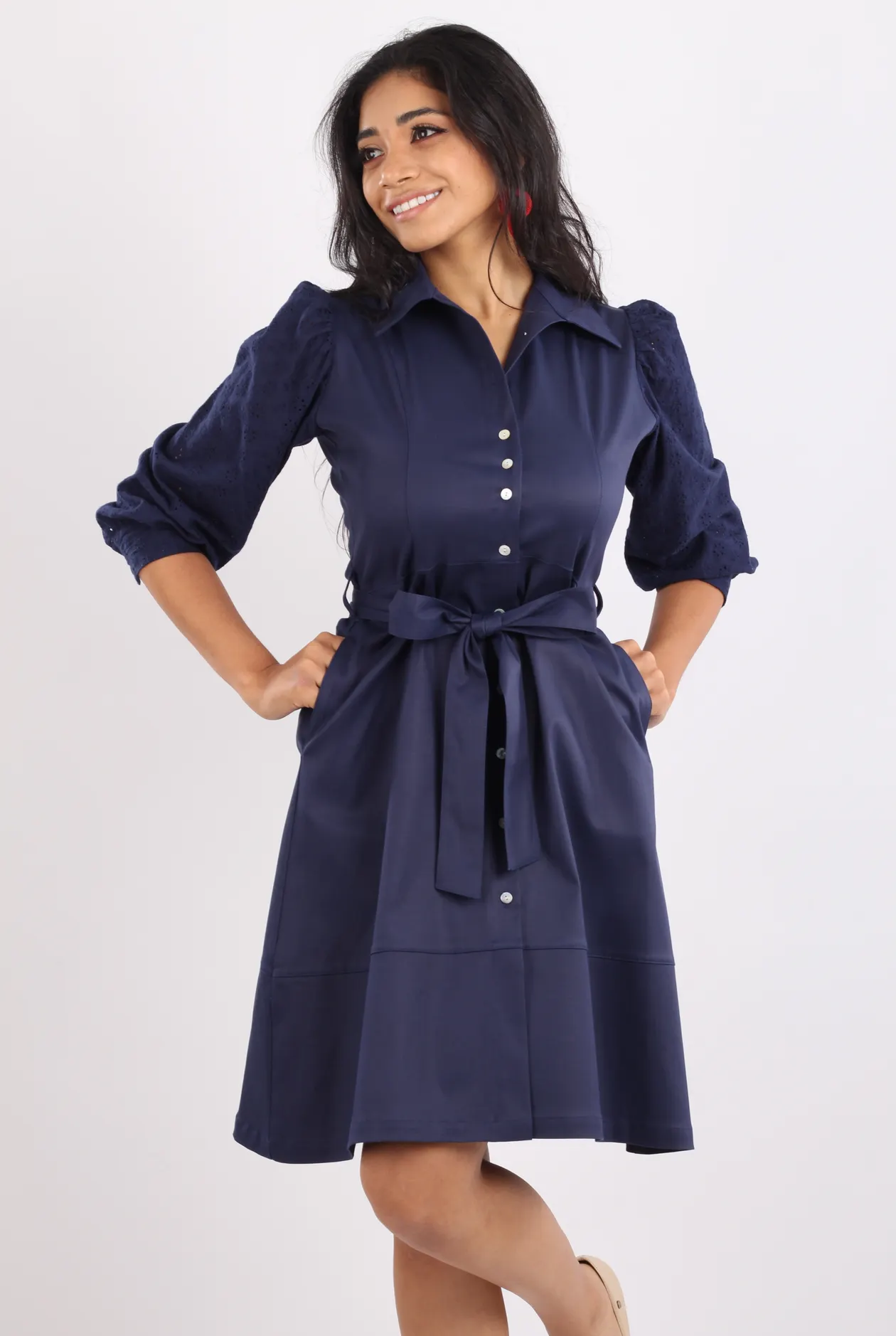 Woman in a navy belted dress against a white background