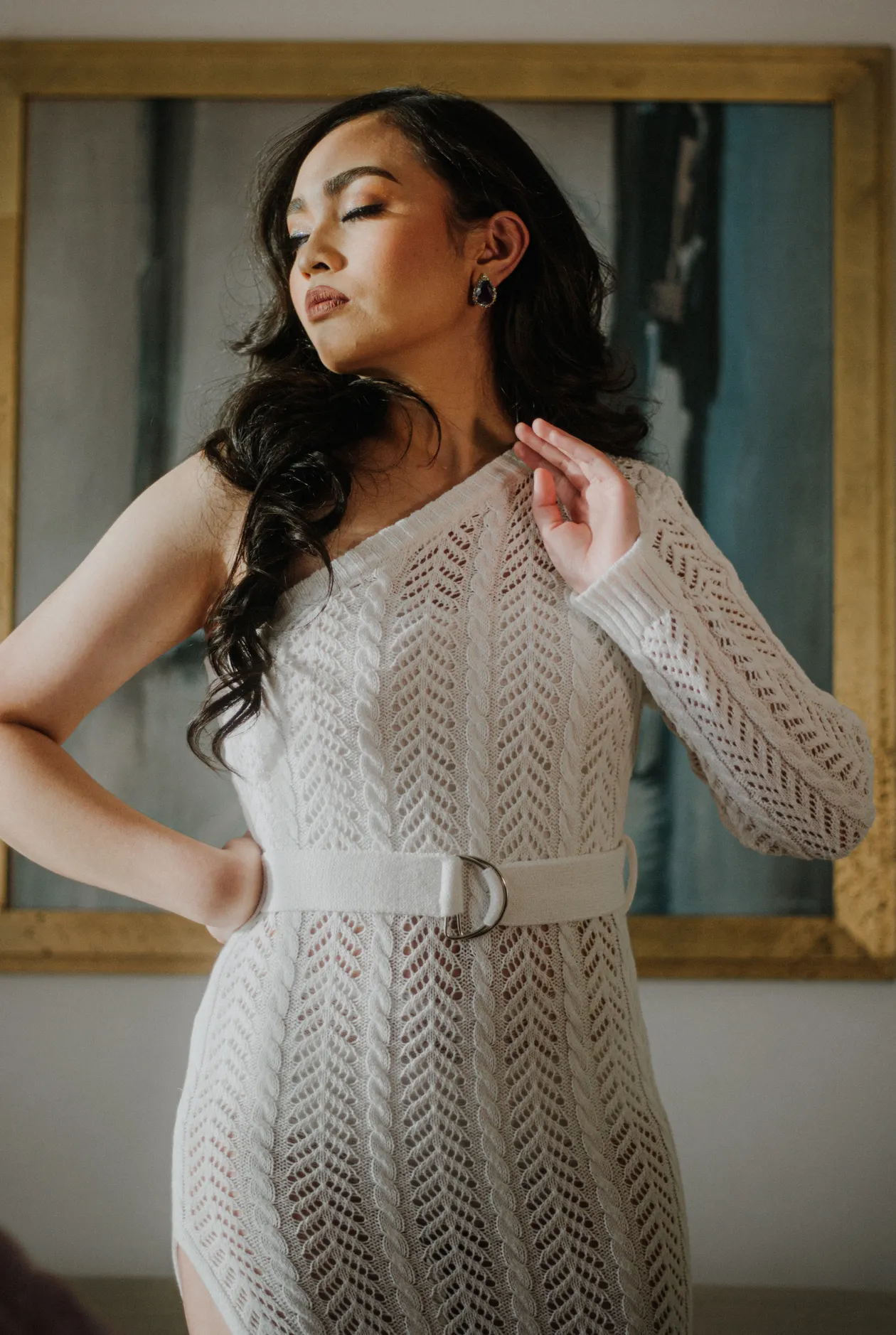 Woman in a white knitted dress with a belt indoors